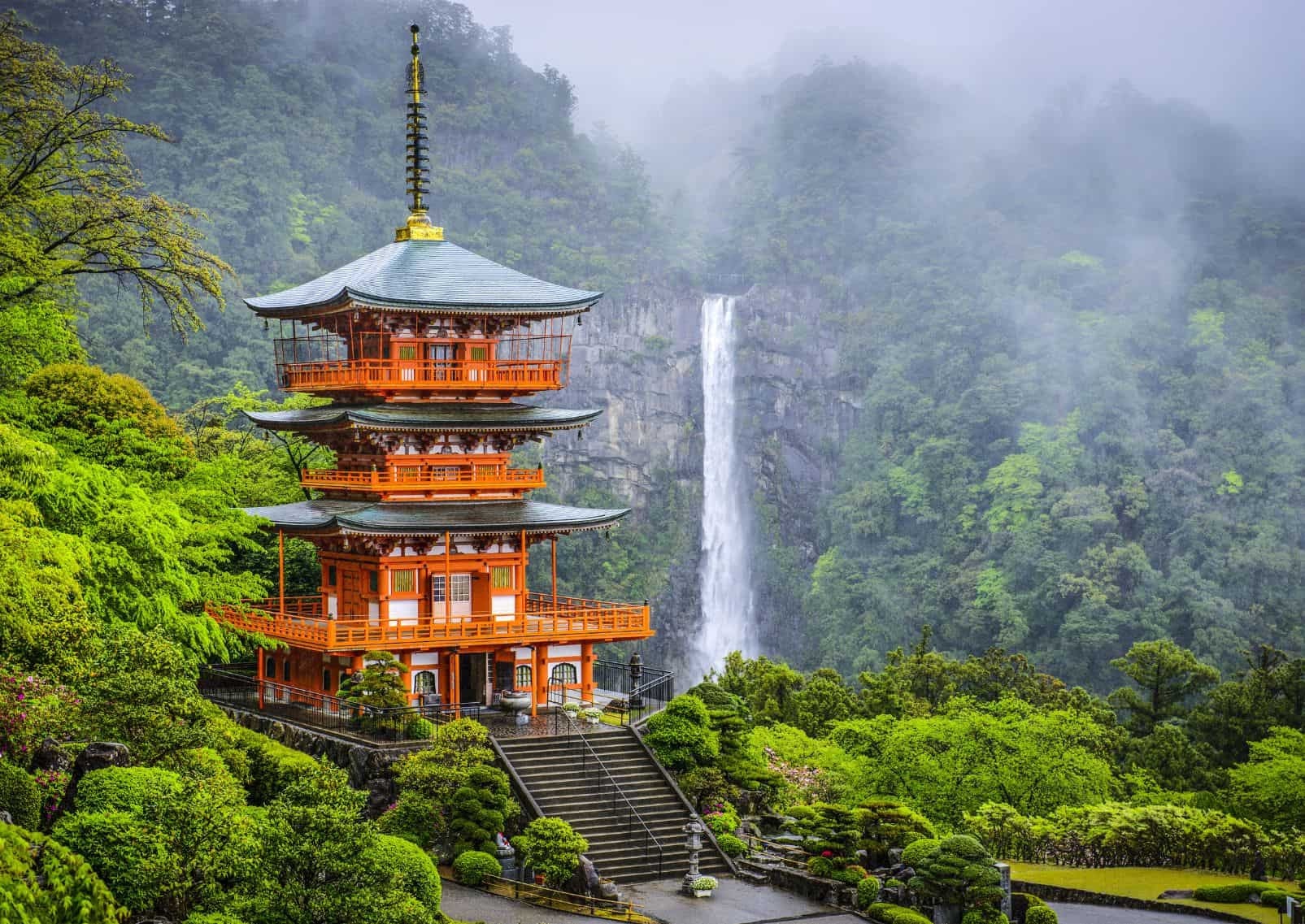 Seigantoji three-story pagoda with Nachi Falls cascading through misty forest behind it, Wakayama