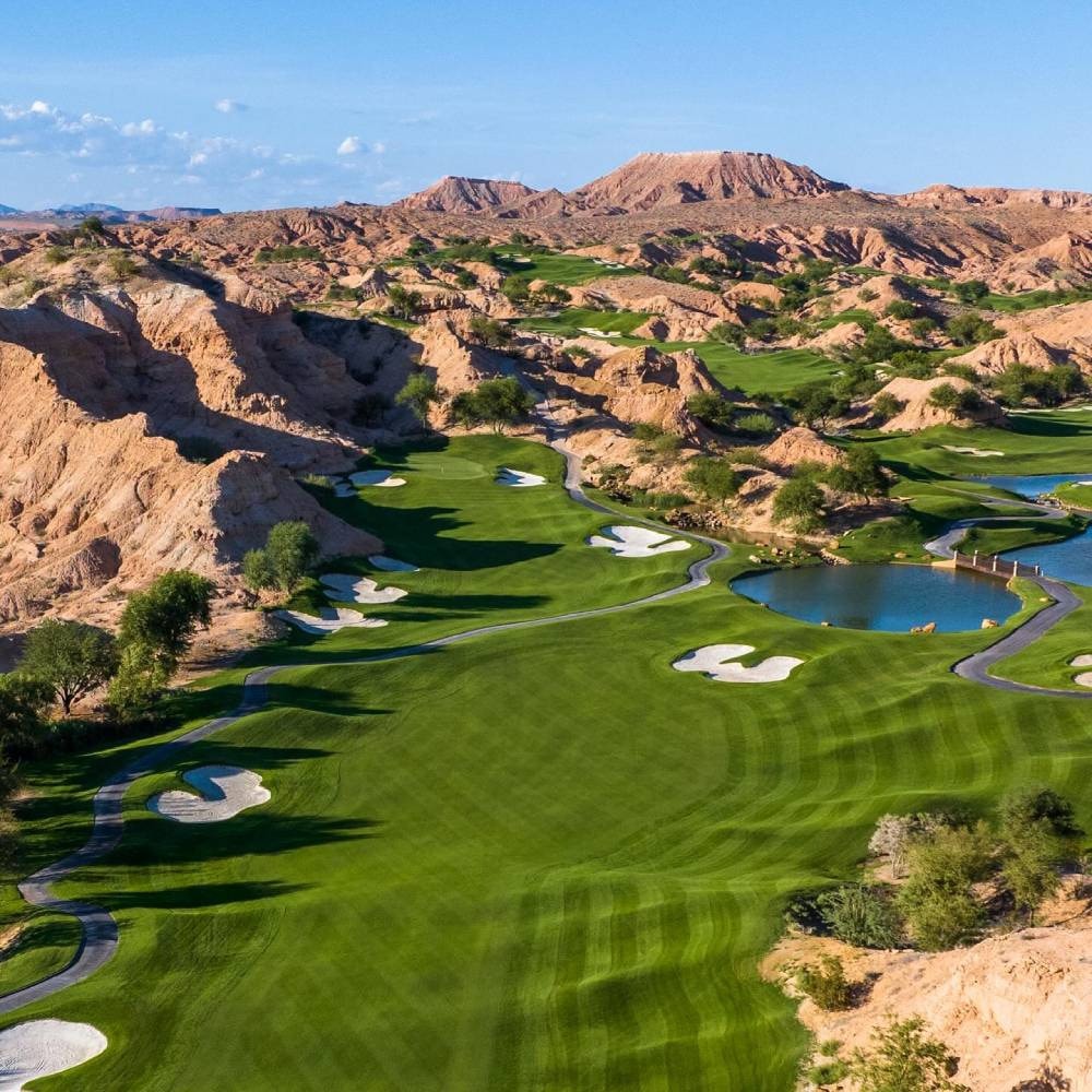 Aerial view of Wolf Creek Golf Club — lush green fairways carved into dramatic red volcanic rock formations, Mesquite NV